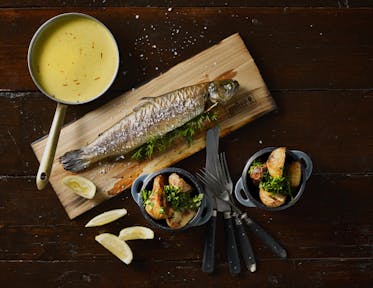 Plank-smoked trout with roast potatoes and creamy saffron sauce