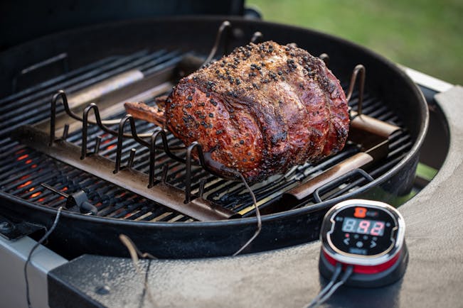 https://content-images.weber.com/content/blog/Grilling-Inspiration/2018-12-Holiday-Lang-How-to-Grill-Prime-Rib-with-a-Fan-Favorite-Recipe-BLOG-PHOTO-Prime-Rib-on-Roasting-Rack-with-iGrill2-on-Performer-4.jpg?auto=compress,format&w=742&h=434