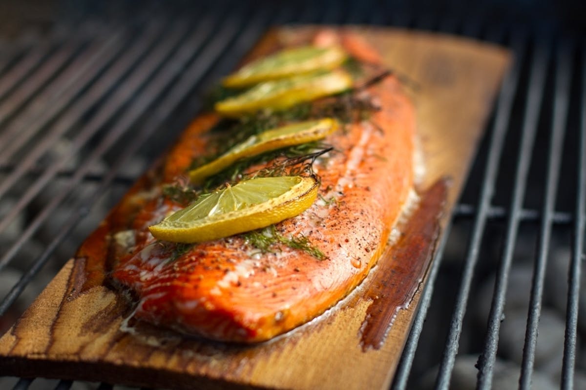 Gewürzter Flammlachs auf einem Räucherbrett auf dem Grillrost