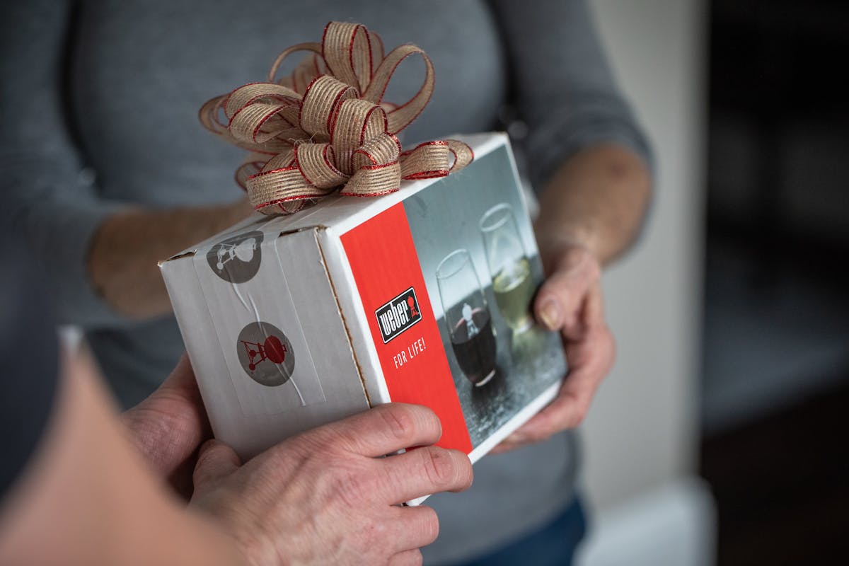  Person handing a box of weber wine glasses 