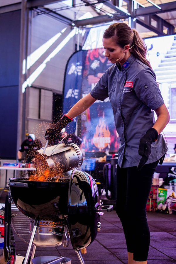 Laura Romeo holding two smoked turkey legs at a competition